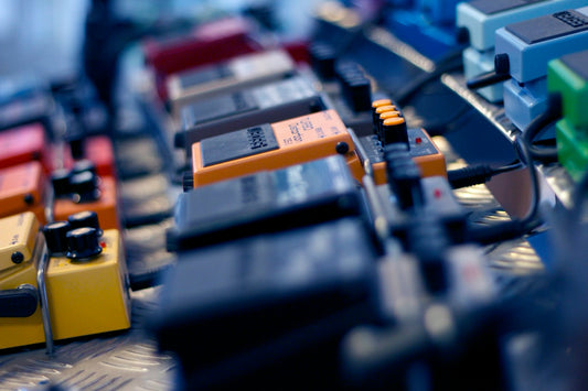 Close-up of guitar effects pedals on a pedalboard with cables connected in a studio setting