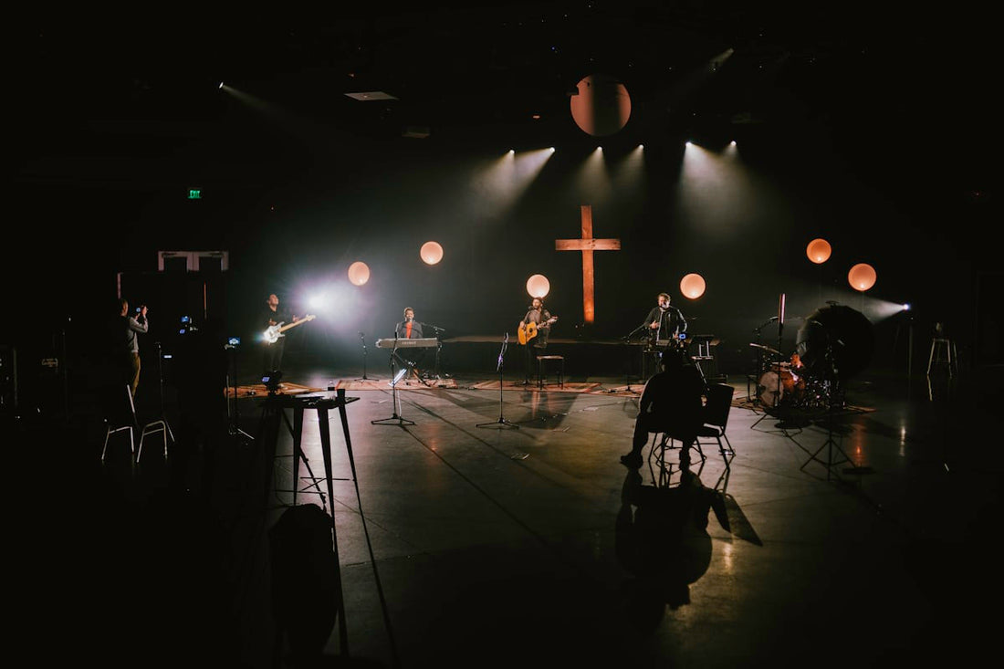 Guitarist playing worship music on stage with ambient lighting and guitar pedalboard