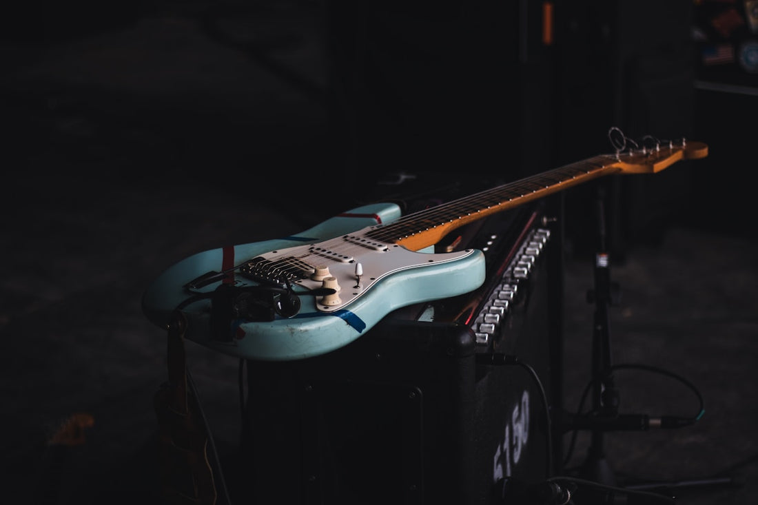 Electric guitar resting on an amplifier head in a moody stage setting