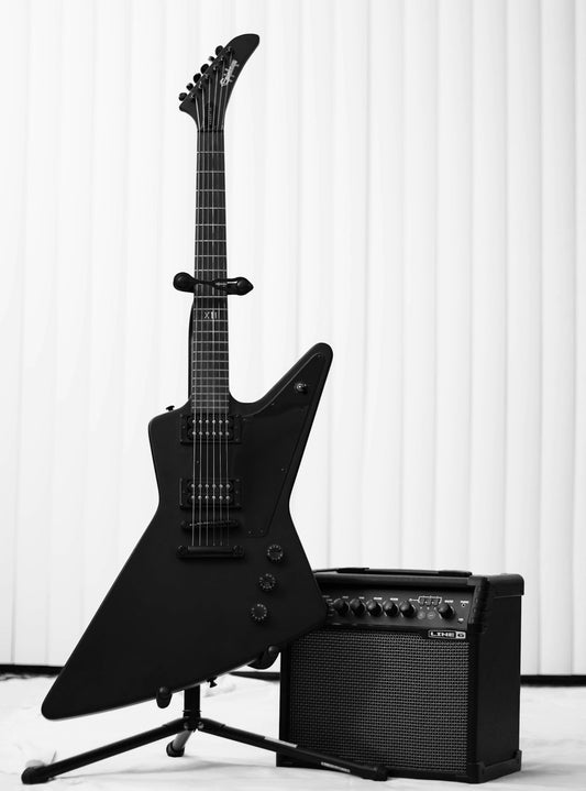 Black electric guitar leaning against a guitar amplifier in a studio setting