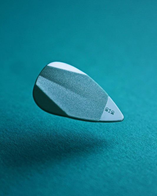 Close-up of a guitar pick striking electric guitar strings showing precise pick attack technique