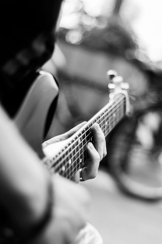 Close-up of a guitarist's hands on an electric guitar fretboard, fingers pressing strings mid-performance