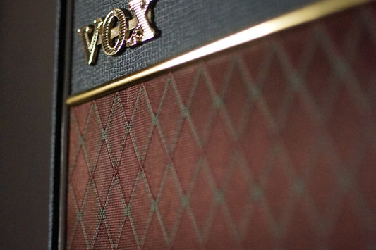 Close-up of a Vox guitar amplifier speaker cabinet showing the speaker grille and logo