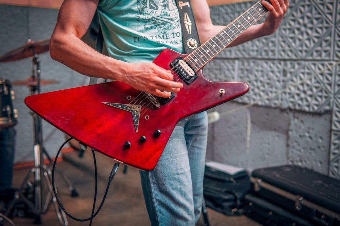 Guitarist playing electric guitar in a studio recording setup with amplifier and gear