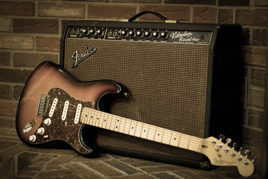 Electric guitar leaning against a vintage tube amplifier in a studio setting