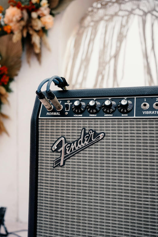 Close-up of a Fender guitar amplifier with volume, treble, middle, and bass knobs